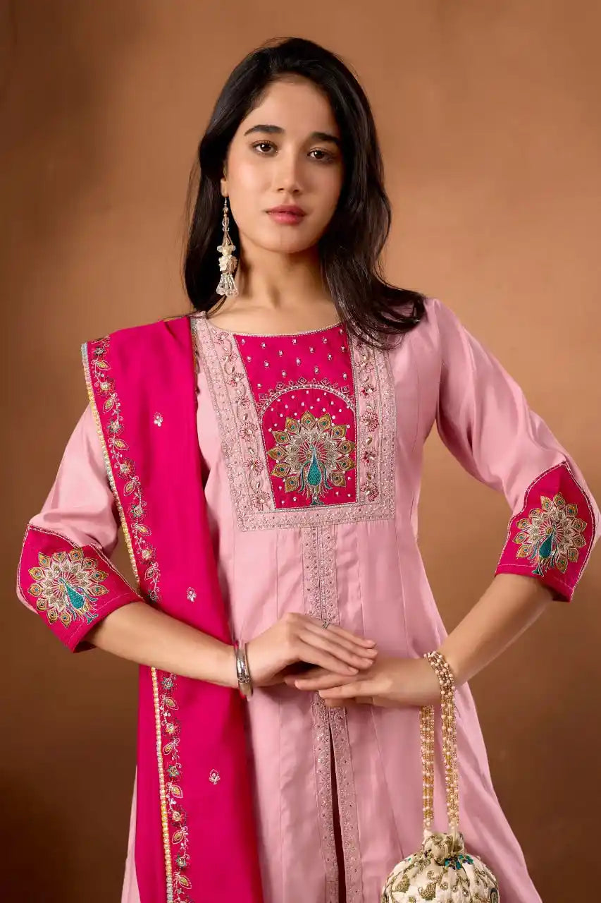 Woman wearing a pink embroidered traditional outfit with a matching dupatta on a brown background